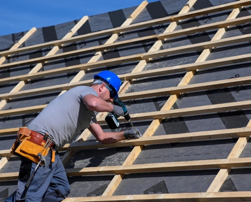 Worker drilling into commercial roof replacement