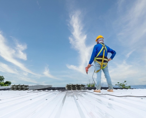 Worker drilling into new metal roof